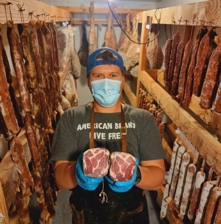 Charcutero de La Vikinga en la cámara de maduración sosteniendo coppa